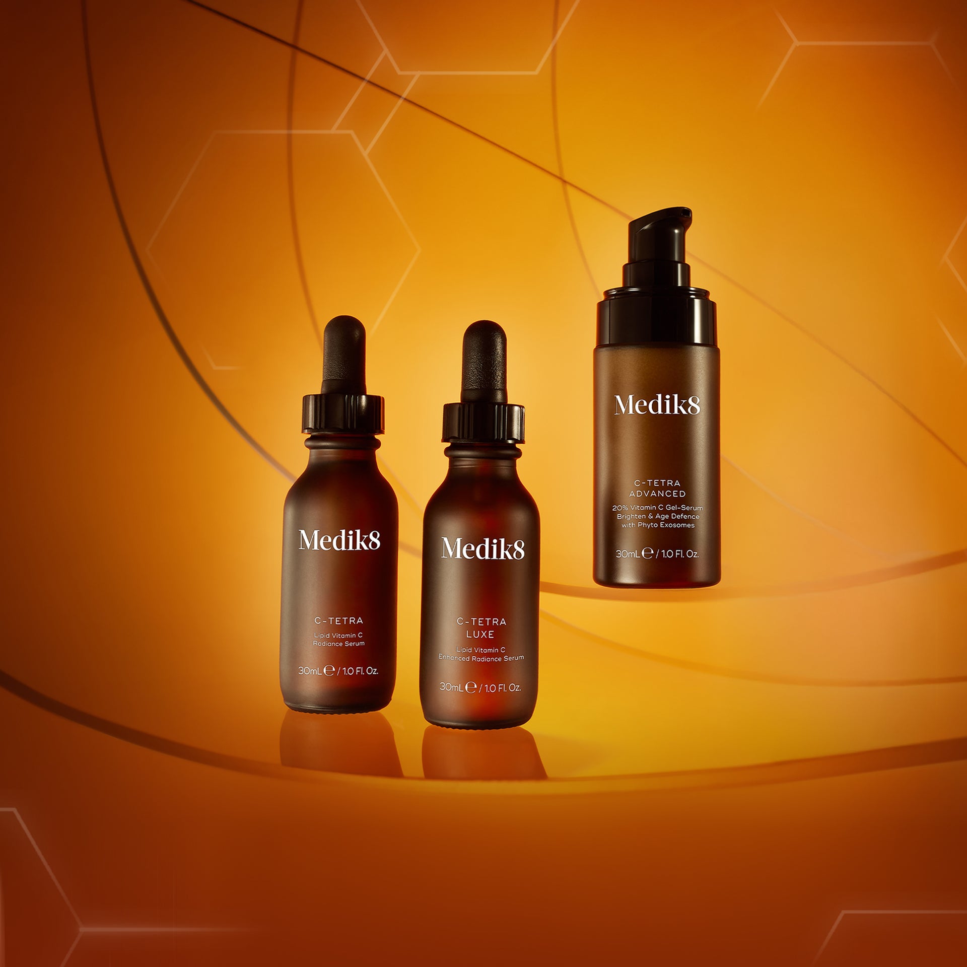 Medik8's full vitamin C serum range displayed against a warm orange background with hexagonal accents. Includes C-Tetra, C-Tetra Luxe, C-Tetra Advanced, and Super C Ferulic, showcasing different formulations for brightening and age-defence.