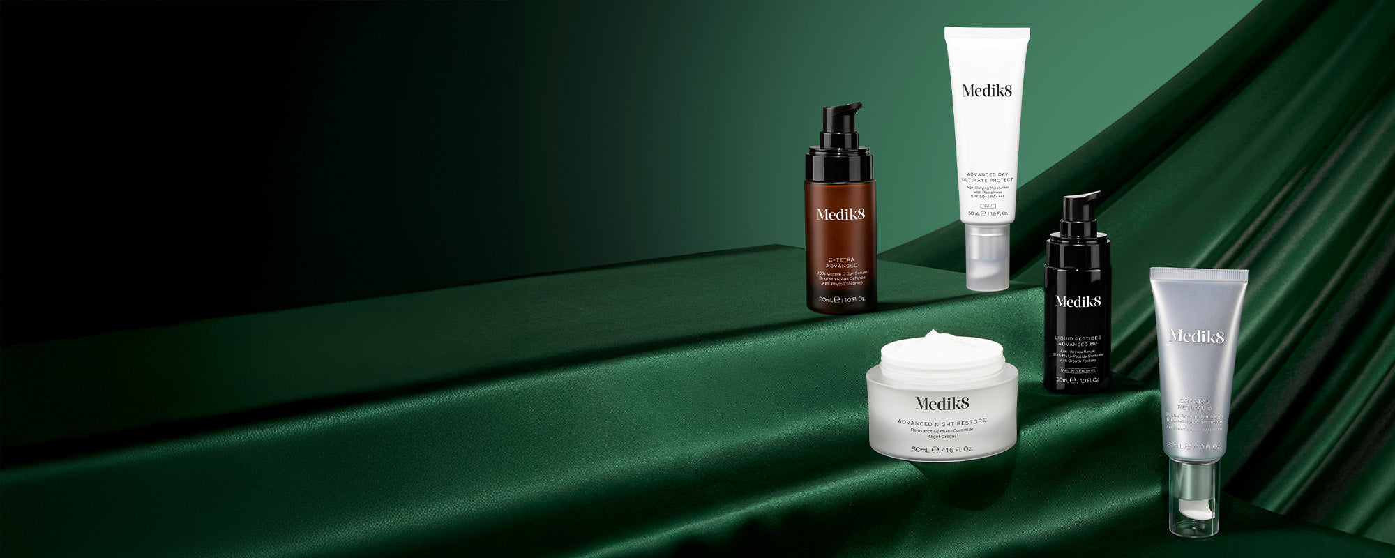 Collection of Medik8 skincare products on a green background