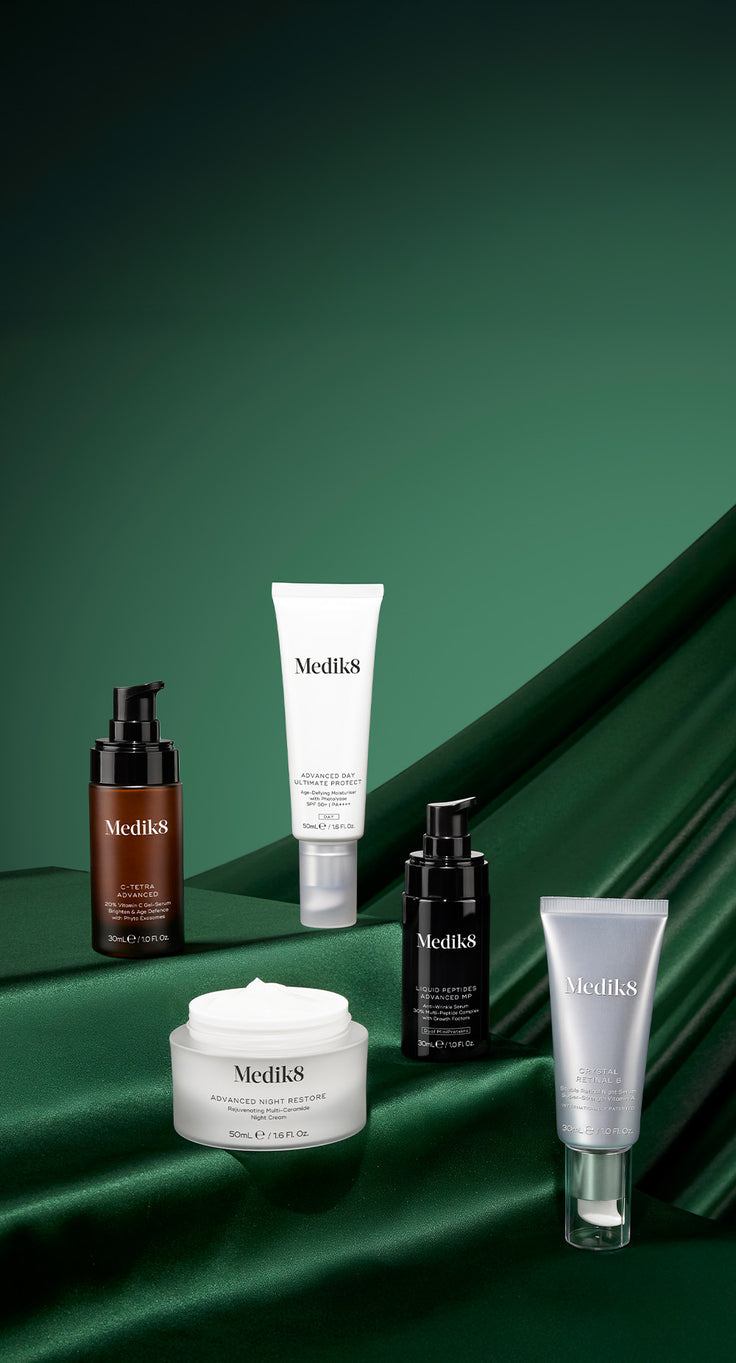 Collection of Medik8 skincare products on a green background