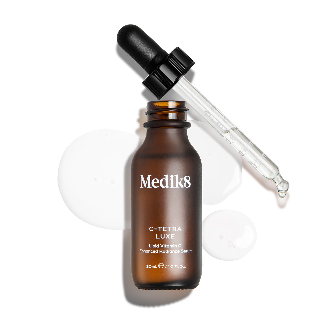 Medik8 C-Tetra Luxe serum bottle shown open with its glass pipette resting against the rim, displayed on a white background with clear, translucent serum droplets.