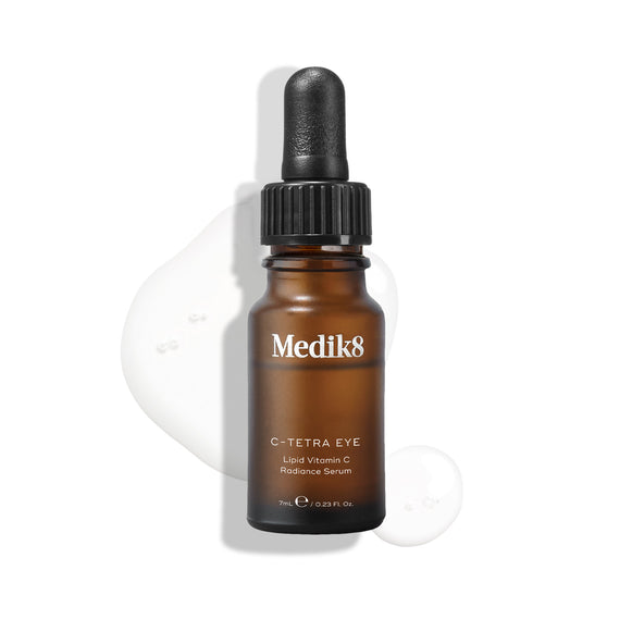 Medik8 C-Tetra Eye Lipid Vitamin C Radiance Serum bottle displayed on a white background with translucent serum droplets, highlighting its liquid texture.-15