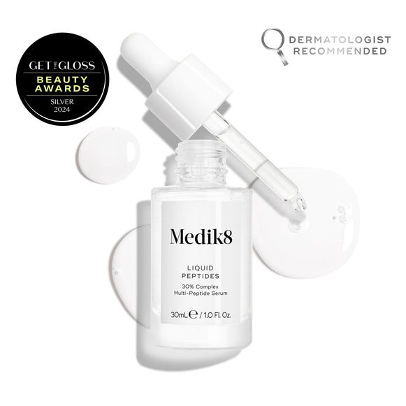 A clear glass dropper bottle of Liquid Peptides serum is presented, with its dropper removed and resting beside it and serum droplets, showing the texture.-11
