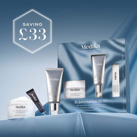 A large, hero image displaying three Medik8 skincare products on a light blue, rippled fabric background. From left to right: a white jar of Medik8 cream, a silver pump bottle of serum, and a smaller white tube of eye cream. The text 'Medik8' is visible on all product labels and in the top left corner of the image. Below the products, the text 'Rejuvenation Reset' is displayed.-78