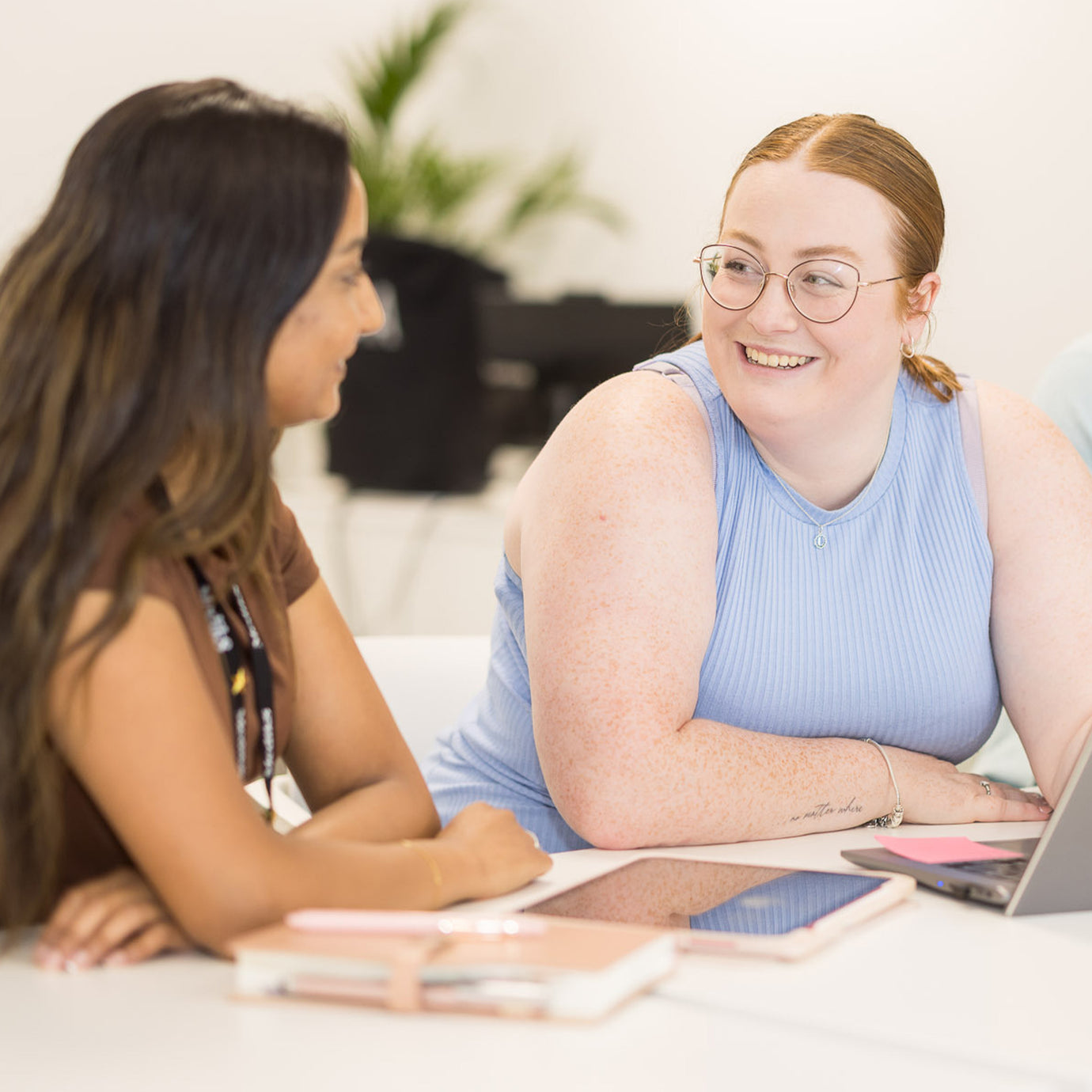 Two Medik8 team members smiling and collaborating in a bright, modern office space, reflecting the brand's commitment to a supportive and inclusive workplace.