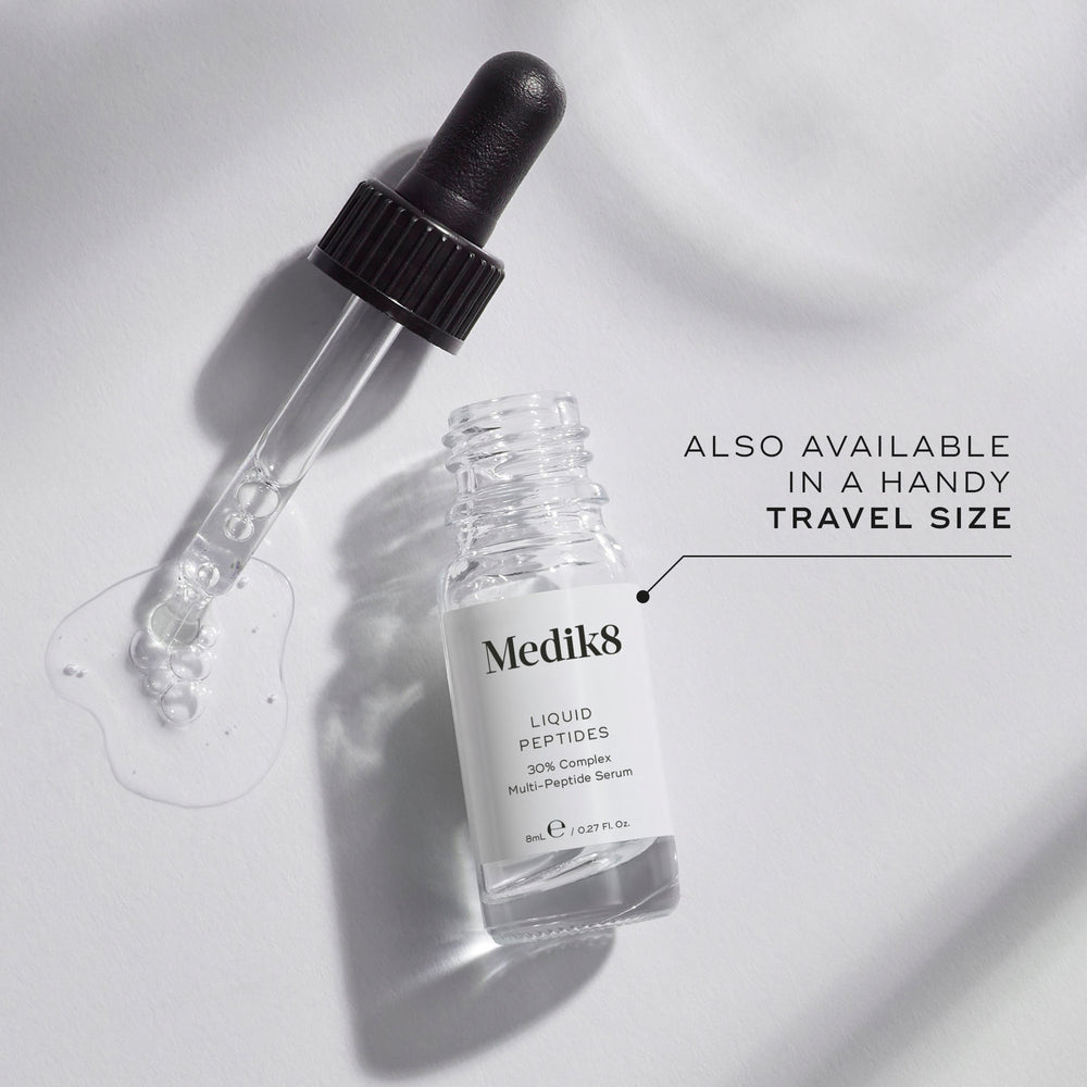 A small clear glass bottle (8mL) of Medik8 Liquid Peptides serum, with its dropper resting beside it. Text indicates it's "ALSO AVAILABLE IN A HANDY TRAVEL SIZE.