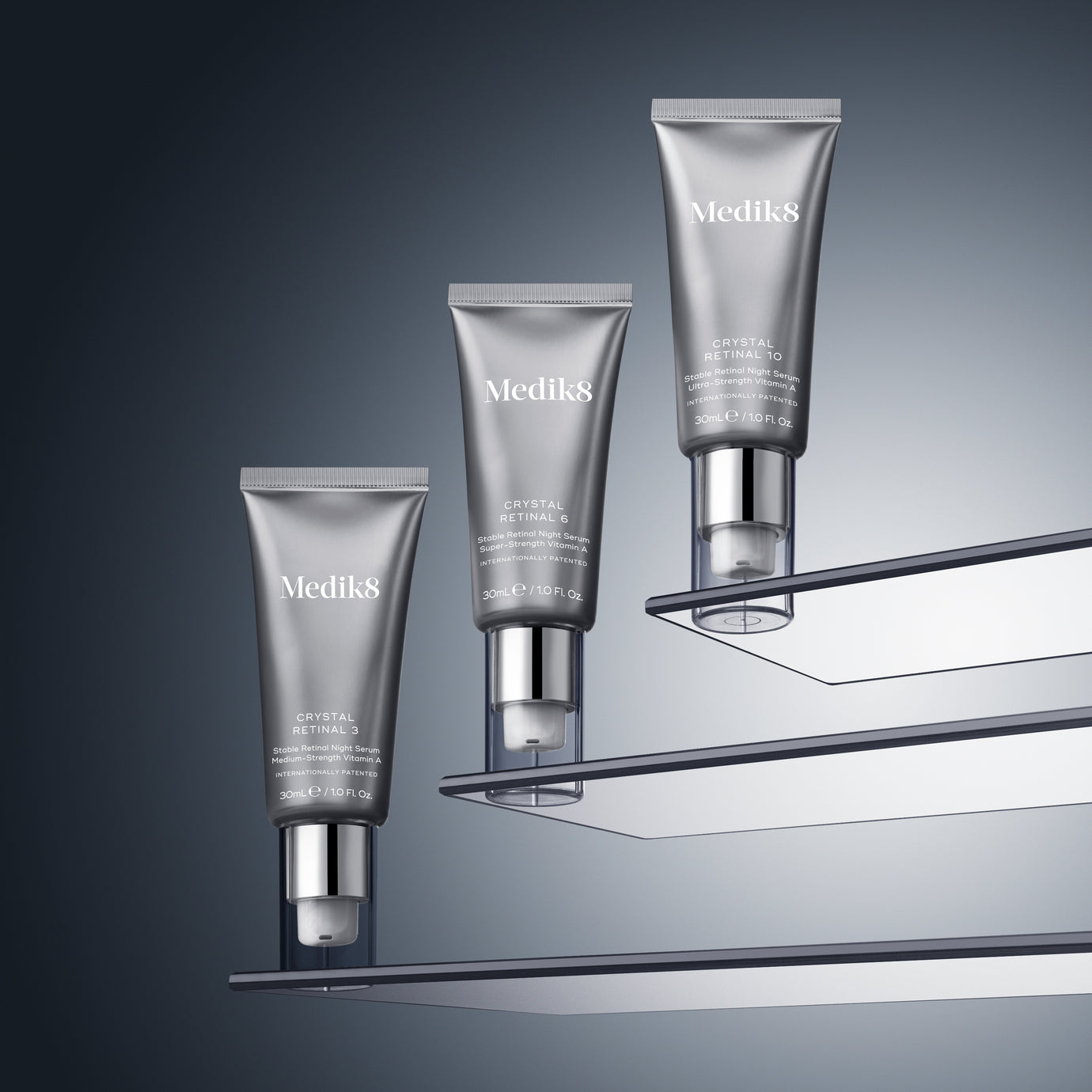 Three silver pump tubes of Medik8 Crystal Retinal displayed ascending on clear, floating glass shelves against a dark grey gradient background. From bottom to top, the tubes are labeled Crystal Retinal 3, Crystal Retinal 6, and Crystal Retinal 10.